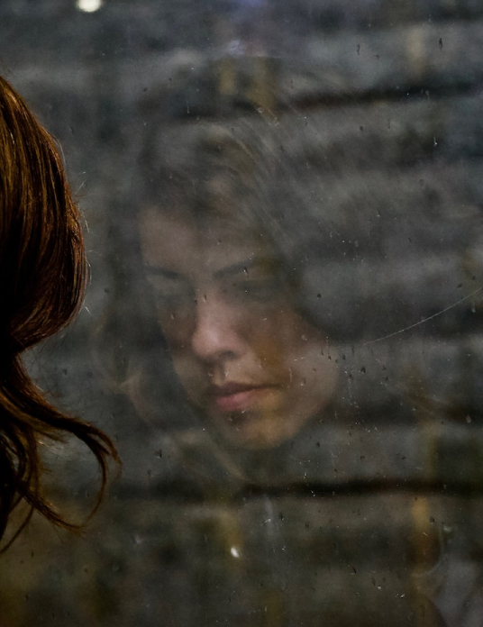 woman looking out window with sad expression